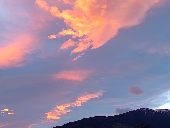 Rot leuchtende Wolken über dunklen Bergen.